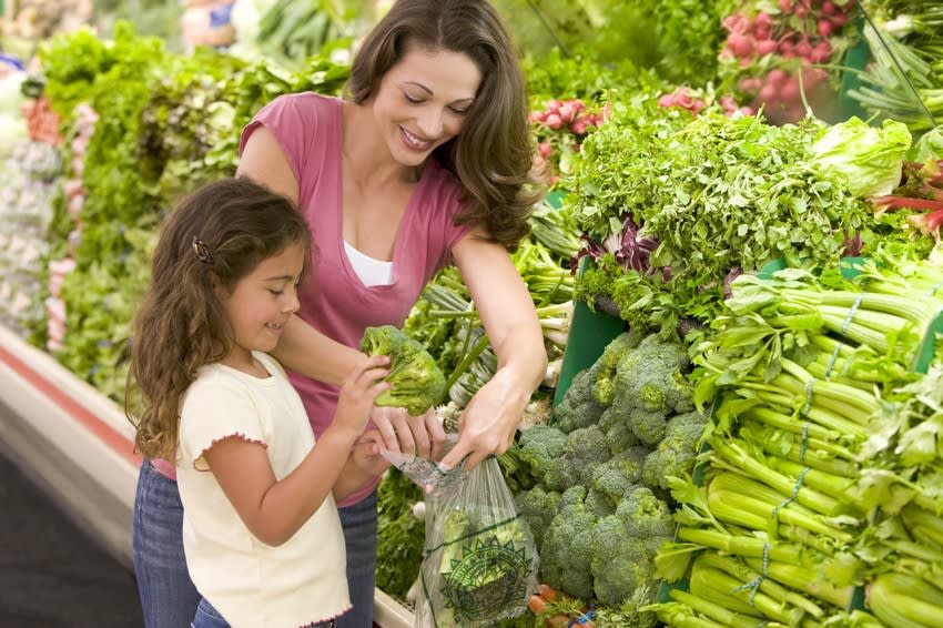 Mother showing daughter how to select produce