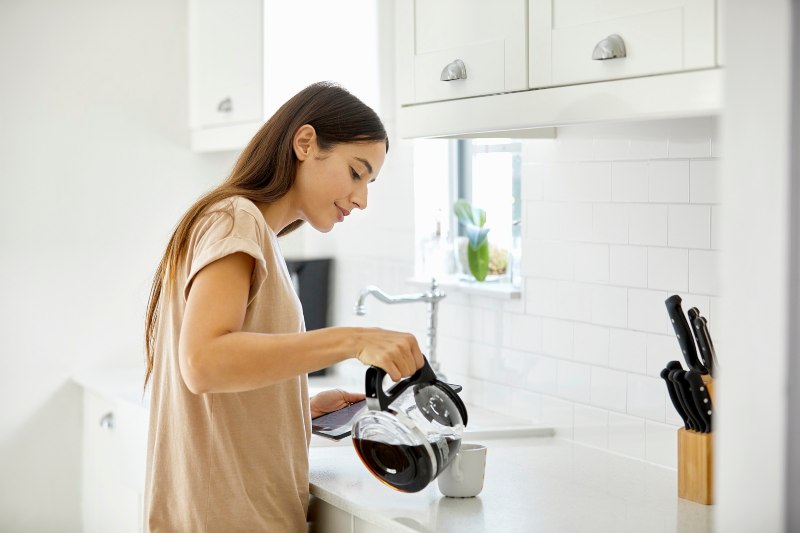 Young woman pouring a fresh brew of coffee into a cup