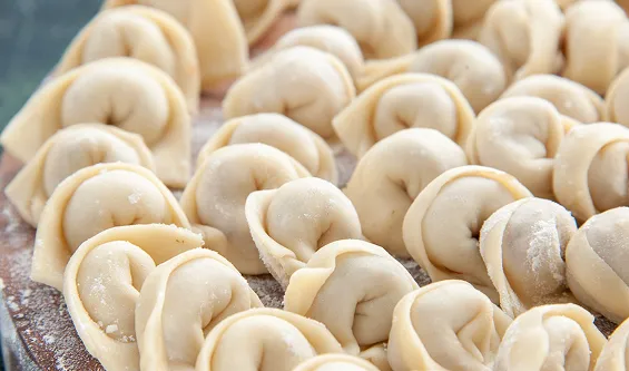 Rows of freshly made pelmeni dumplings on a wooden board