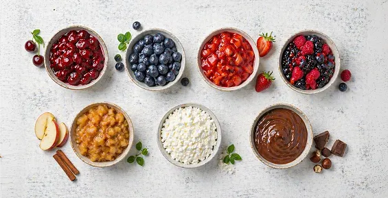 Seven bowls of sweet dumpling fillings including berries, cottage cheese and chocolate